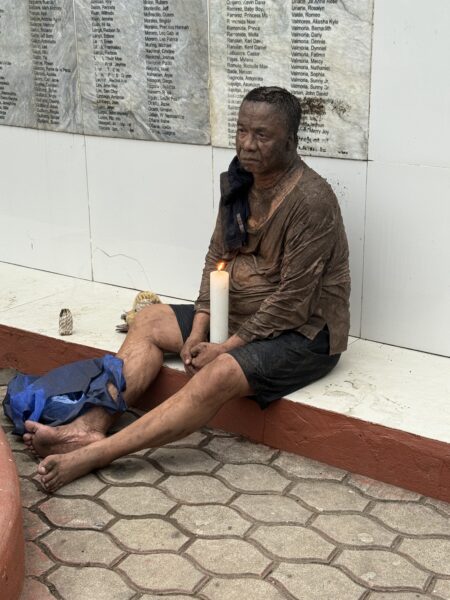 Performance artist Nic Aca pays tribute at the Sendong Memorial Wall in Gaston Park, Cagayan de Oro, during the 14th anniversary of Tropical Storm Sendong.