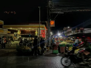 Night view of Cogon Market in Cagayan de Oro with motorists and street vendors near a Shell gas station during a period of rising global oil prices.