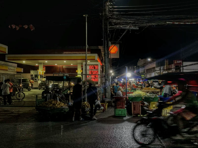 Night view of Cogon Market in Cagayan de Oro with motorists and street vendors near a Shell gas station during a period of rising global oil prices.