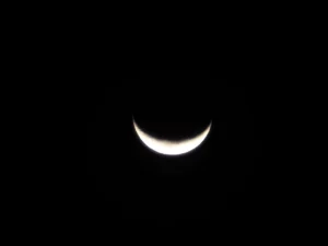 Close-up of a thin waxing crescent moon (Hilal) in the night sky