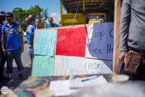 Iligan jeepney drivers during a transport strike stand beside a large multi-colored protest sign that demands: "OIL DEREGULATION IBASURA" and "SUSPEND EXCISE TAX AT VAT."
