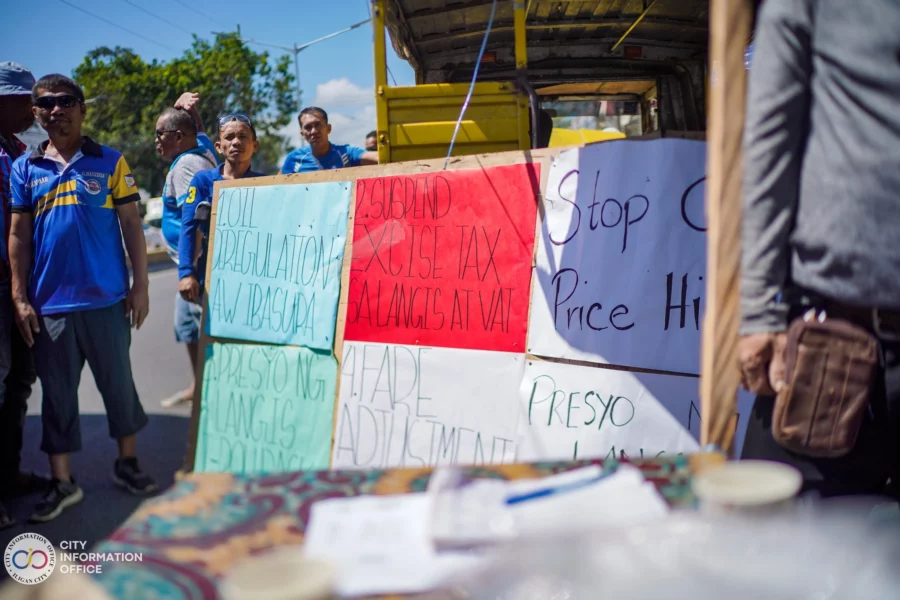 Iligan jeepney drivers during a transport strike stand beside a large multi-colored protest sign that demands: "OIL DEREGULATION IBASURA" and "SUSPEND EXCISE TAX AT VAT."
