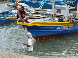 Local fishermen sitting beside a docked fishing vessel at Luyongbonbon pier in Opol, Misamis Oriental, during a fuel price hike.