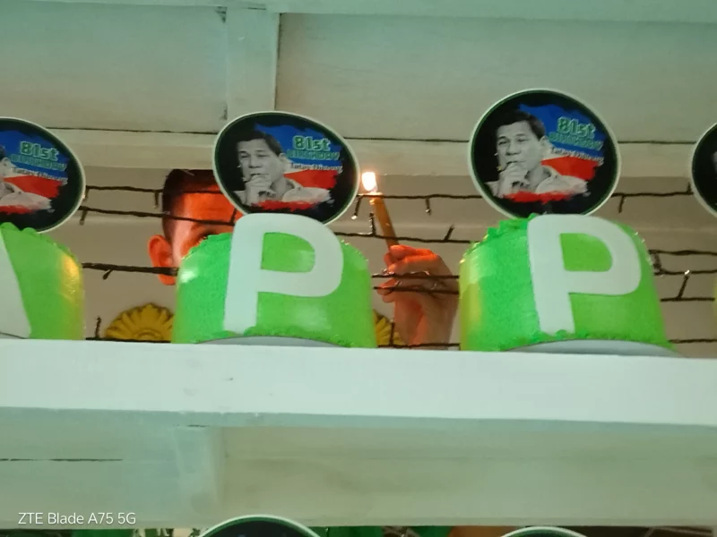 A supporter lighting one of 81 cakes during the 81st birthday celebration for former President Rodrigo Duterte at Divisoria Kiosko in Cagayan de Oro.
