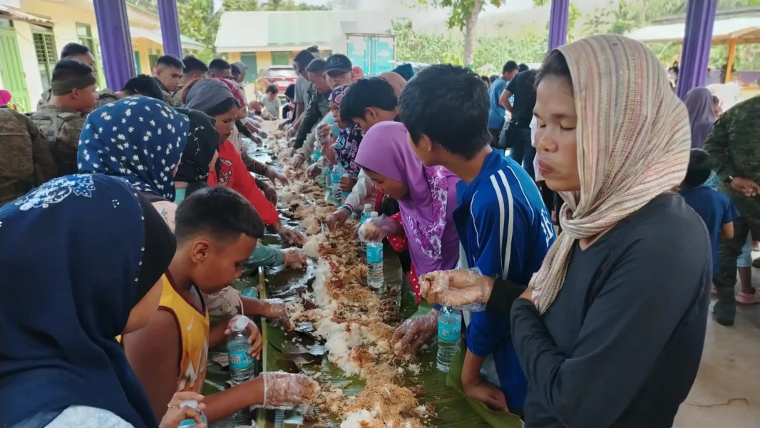 Soldiers, volunteers, and Omayamnon community members participating in a traditional boodle fight in Tagoloan.