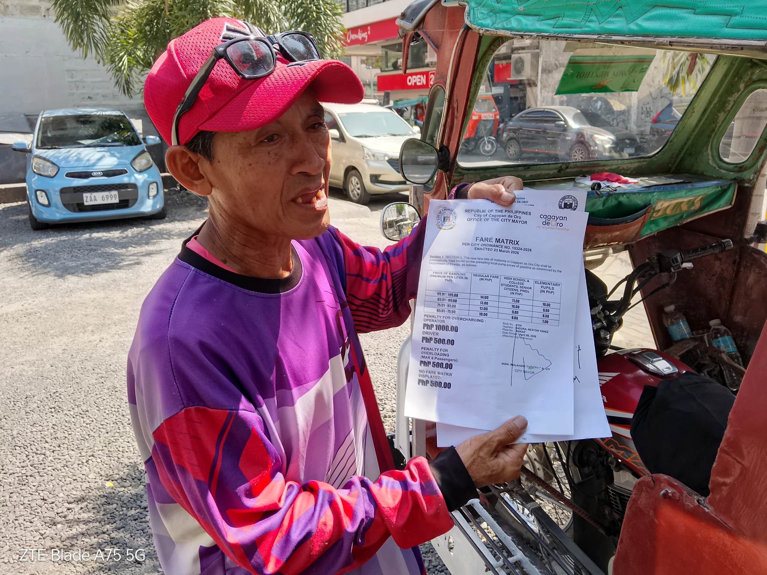 Motorela driver Nestor Sadura showing the official P14 minimum fare matrix approved by the Cagayan de Oro City Council.