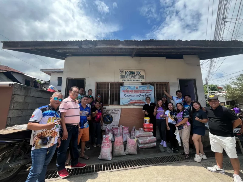 Leaders of the Tagoloan Eagles and Lady Eagles Clubs standing alongside local officials outside the Losina Child Development Center with donated school supplies and cement bags.