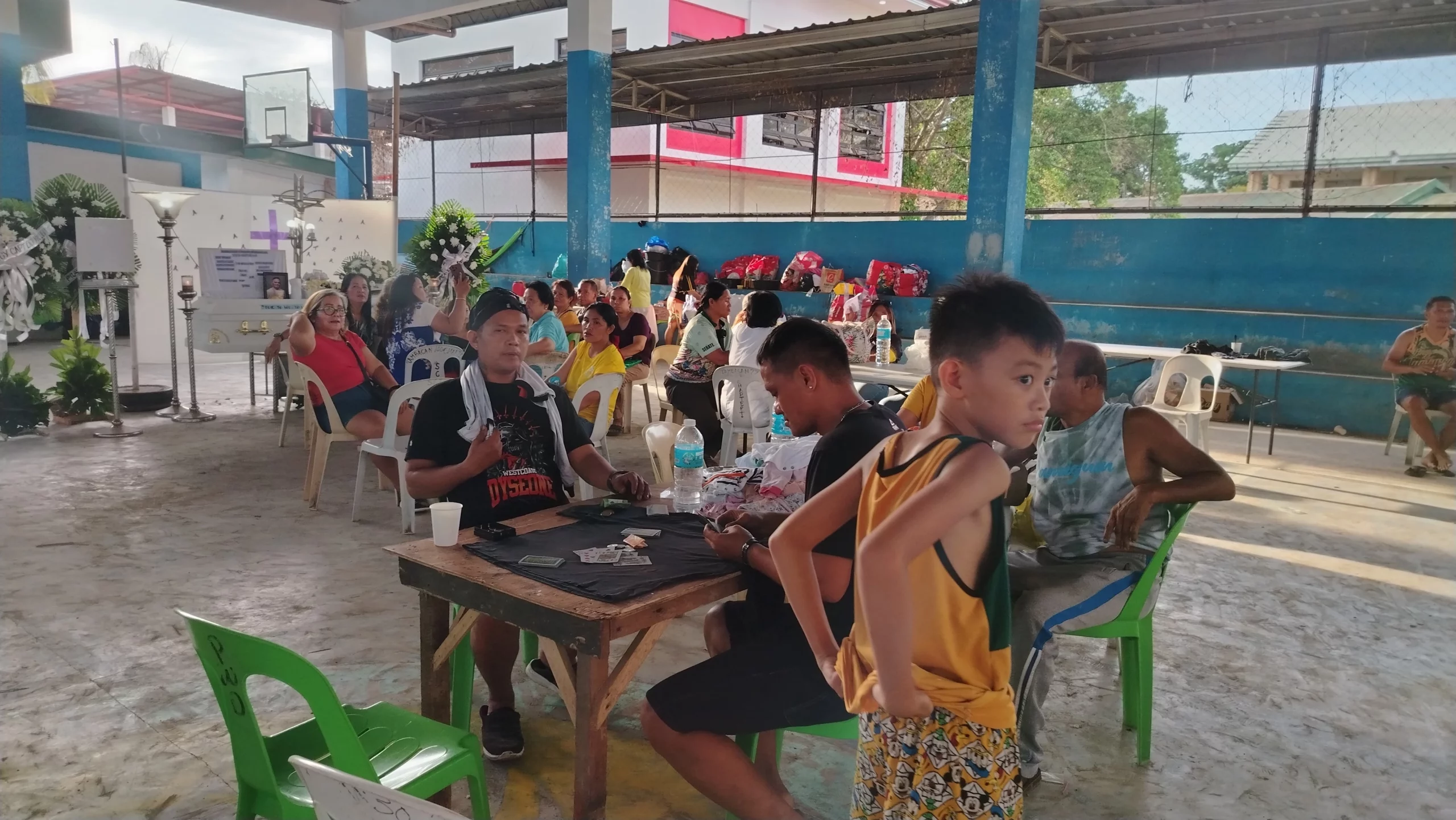 Displaced families sitting with their belongings inside a barangay gymnasium, which serves as a temporary evacuation center.