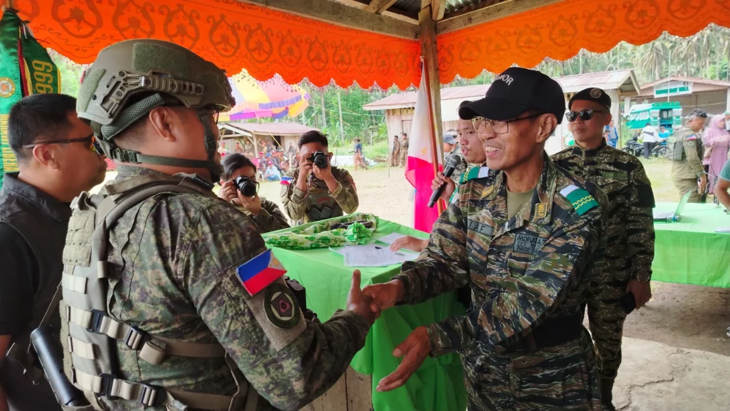 Officials and commanders from the MILF 127th Bilal Base Command, Philippine Army 44th Infantry Battalion, and Munai Municipal Police Station holding signed peace resolutions during a community gathering.