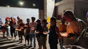 Displaced steel factory workers and family members holding lit candles during a nighttime protest outside the plant gates in Tagoloan.