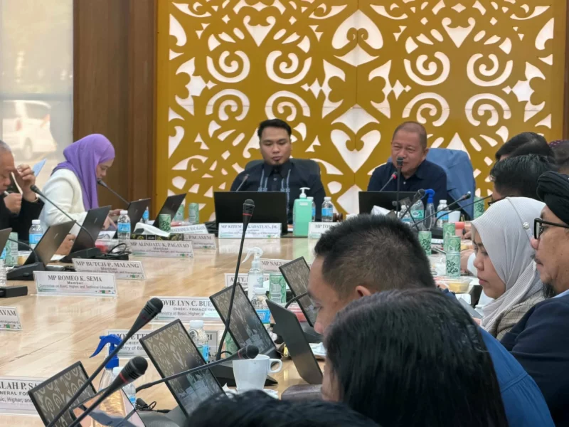 Members of the Bangsamoro Transition Authority Parliament sit at long conference tables inside the Pangalian M. Balindong Hall in Cotabato City during an oversight hearing with education officials.