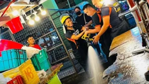 City personnel using high-pressure water hoses to wash concrete pathways and clear drainage systems inside the Cogon Public Market in Cagayan de Oro.