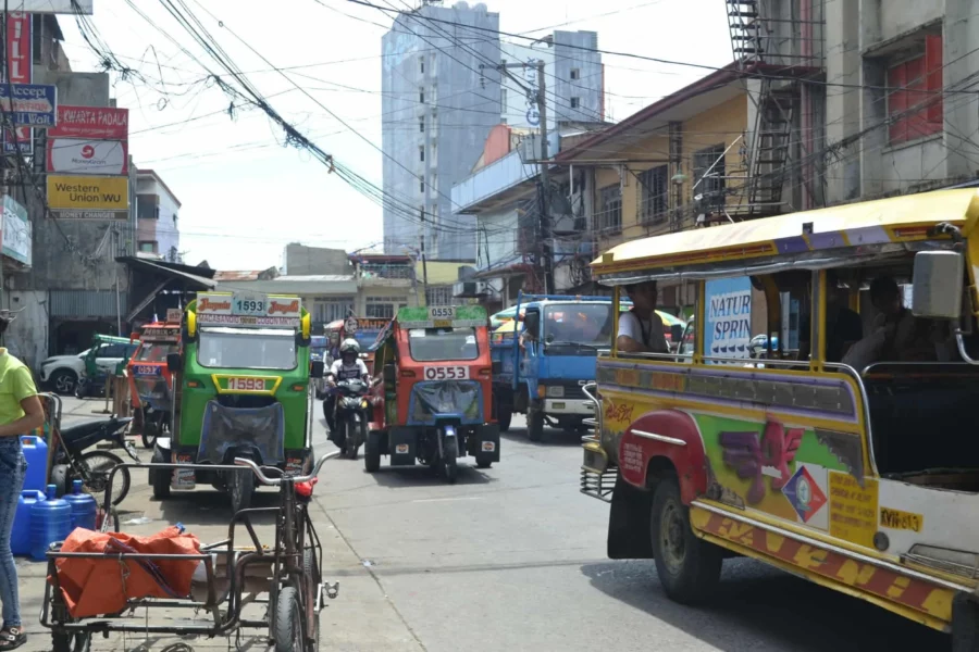 A street-level view of public utility jeepneys and localized three-wheeled motorelas lined up along the busy transit lanes outside Cogon Public Market in Cagayan de Oro City.