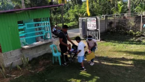 A campus security guard conducts a bag inspection and verifies identification cards at a public school entrance gate in Davao City.