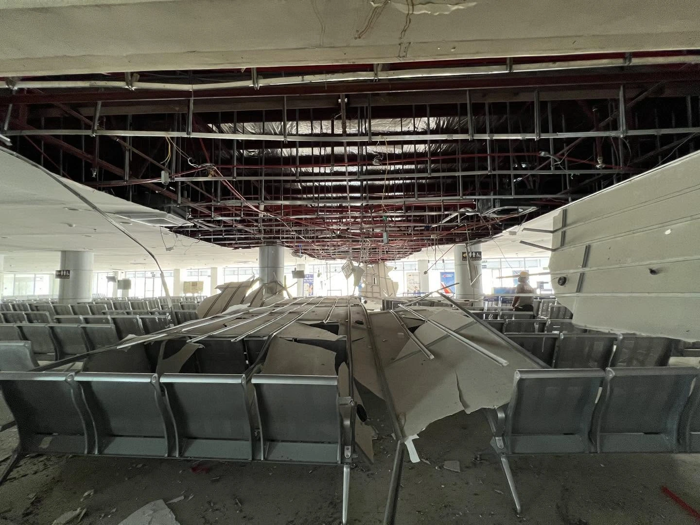 Debris from a collapsed drywall and metal grid ceiling litters rows of silver passenger chairs inside the General Santos International Airport terminal after a magnitude 7.8 earthquake.