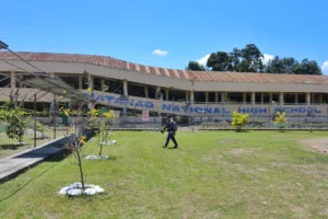 A man walks past a heavily damaged, collapsed concrete school building at Matanao National High School in Davao del Sur following the magnitude 7.8 Mindanao earthquake.