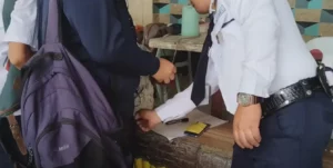 A security guard in a uniform inspects and frisks high school students one by one at the entrance gates of Misamis Oriental General Comprehensive High School.