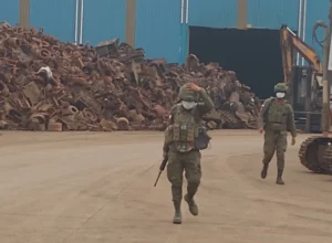 Soldiers walking past large stockpiles of impounded scrap metal inside the Philippine Sanjia Steel Corporation compound in Tagoloan, Misamis Oriental.