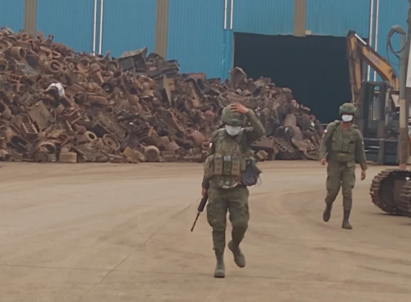 Soldiers walking past large stockpiles of impounded scrap metal inside the Philippine Sanjia Steel Corporation compound in Tagoloan, Misamis Oriental.