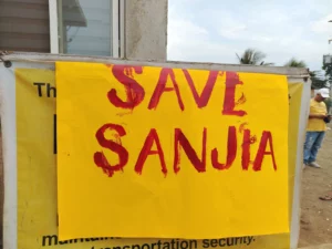 A bright yellow protest placard with the words "SAVE SANJIA" painted in bold red letters, displayed outdoors following the legal dispute and raid in Tagoloan, Misamis Oriental.