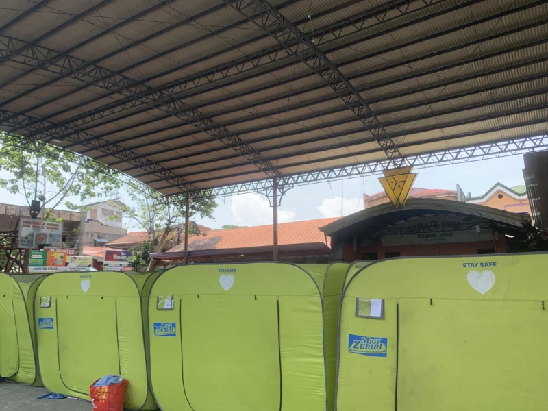 Displaced families sitting near modular tents and supplies inside a crowded municipal evacuation center in Barangay Lapasan, Cagayan de Oro City, following a neighborhood fire in Santo Niño.