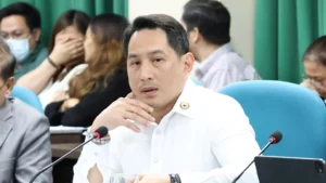 Lanao del Sur Representative Ziaur-Rahman Adiong stands at a podium speaking into microphones during a press conference outside the city prosecutor office.