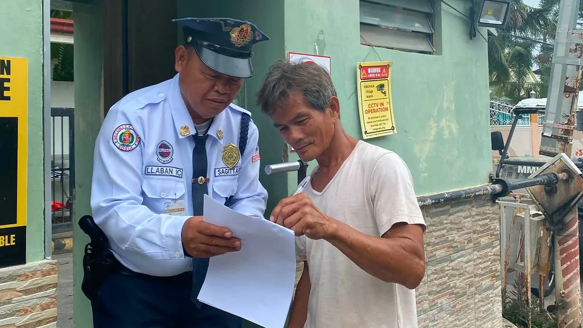 A Morning Mist Village resident signs a signature campaign document held by a security guard outside the village's guardhouse in Cagayan de Oro City. HOA members organized the petition drive to oppose state housing regulators replacing their elected leadership prior to their scheduled Aug. 22 voting date. (Photo Courtesy of Arthur Aranas)