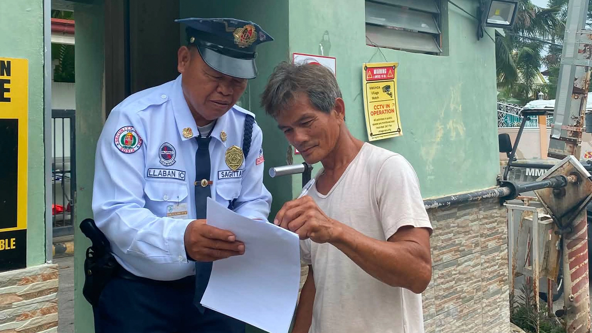 A Morning Mist Village resident signs a signature campaign document held by a security guard outside the village's guardhouse in Cagayan de Oro City. HOA members organized the petition drive to oppose state housing regulators replacing their elected leadership prior to their scheduled Aug. 22 voting date. (Photo Courtesy of Arthur Aranas)