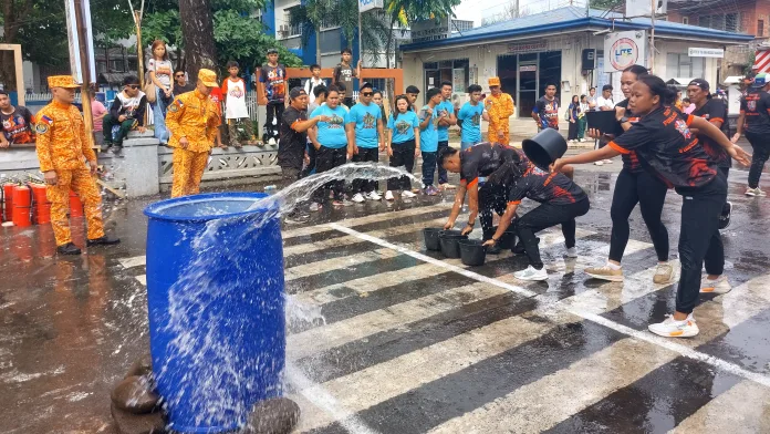 Members of the Barangay South Poblacion fire safety response team splash water into a structural barrel during a bucket relay race in Medina, Misamis Oriental.