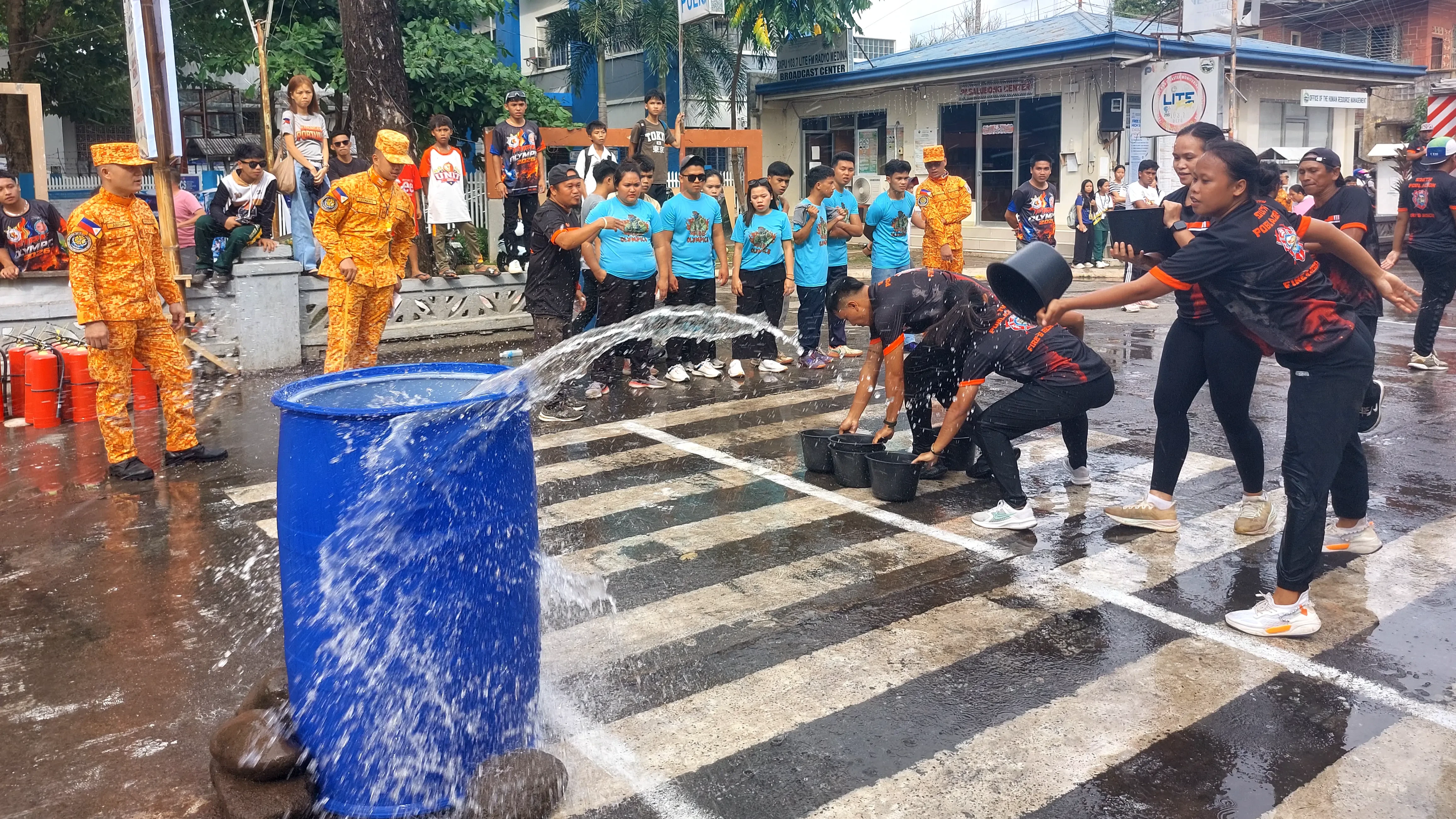 Members of the Barangay South Poblacion fire safety response team splash water into a structural barrel during a bucket relay race in Medina, Misamis Oriental.