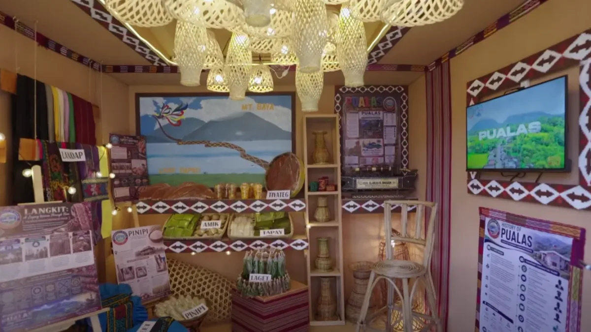 A cultural exhibition booth representing Pualas, Lanao del Sur, showcases traditional Maranao textiles, local delicacies, and regional handicrafts during a provincial heritage festival on July 8, 2026. The display features handwoven langkit fabrics, native agricultural products, and artwork depicting Mt. Baya and Lake Dapao to promote localized eco-tourism. (Screengrabbed from the Lanao del Sur Provincial Tourism Office)