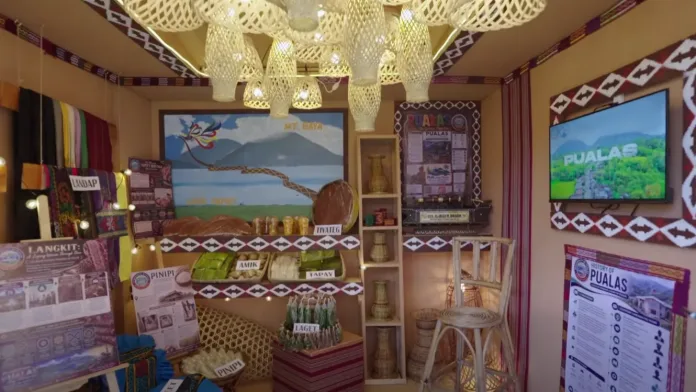 A cultural exhibition booth representing Pualas, Lanao del Sur, showcases traditional Maranao textiles, local delicacies, and regional handicrafts during a provincial heritage festival on July 8, 2026. The display features handwoven langkit fabrics, native agricultural products, and artwork depicting Mt. Baya and Lake Dapao to promote localized eco-tourism. (Screengrabbed from the Lanao del Sur Provincial Tourism Office)