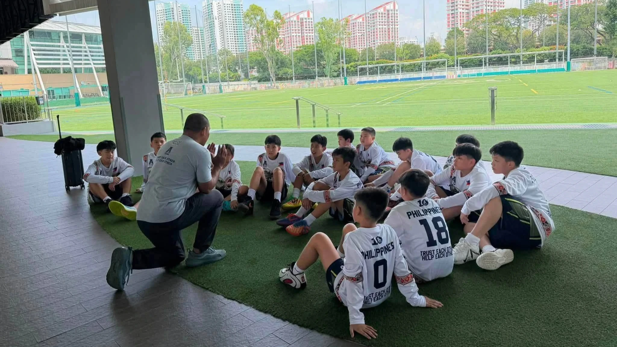 TEAM HUDDLE. Coach Arvin Martinez kneels as he addresses players of the Northern Mindanao A-Team during a team talk at the Australian International School in Singapore during the 3rd World Youth Championship. The Cagayan de Oro-based squad overcame administrative and financial hurdles—along with emergency surgery for starting guard Leba Deomidi “LD” Martinez—to sweep the tournament and capture the championship title. (Photo courtesy of A-Team Basketball Program)