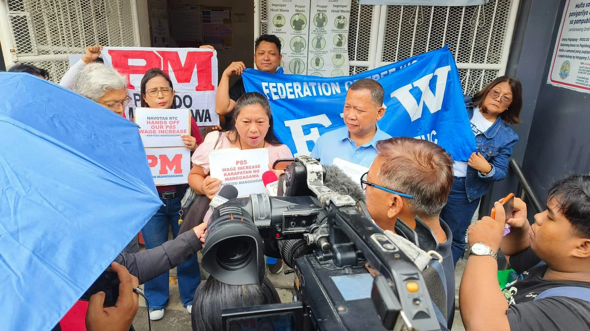 FFW President Atty. Sonny G. Matula (center, in blue) speaks to reporters outside the Navotas City Hall of Justice after the Federation of Free Workers (FFW) and the NAGKAISA! Labor Coalition filed a motion to intervene in a court case challenging the implementation of the ₱85 daily minimum wage increase for Metro Manila workers on Wednesday, Aug. 6. (Photo courtesy of FFW)