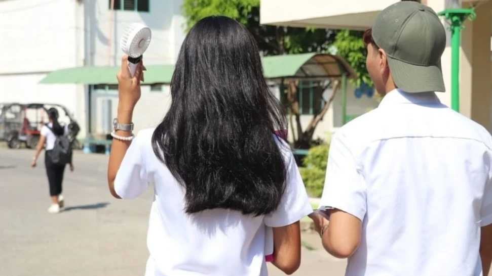 Students use portable fans to beat the heat on campus as at least 20 local government units across Misamis Oriental suspend classes due to a dangerous 43°C heat index forecast. PIA PHOTO