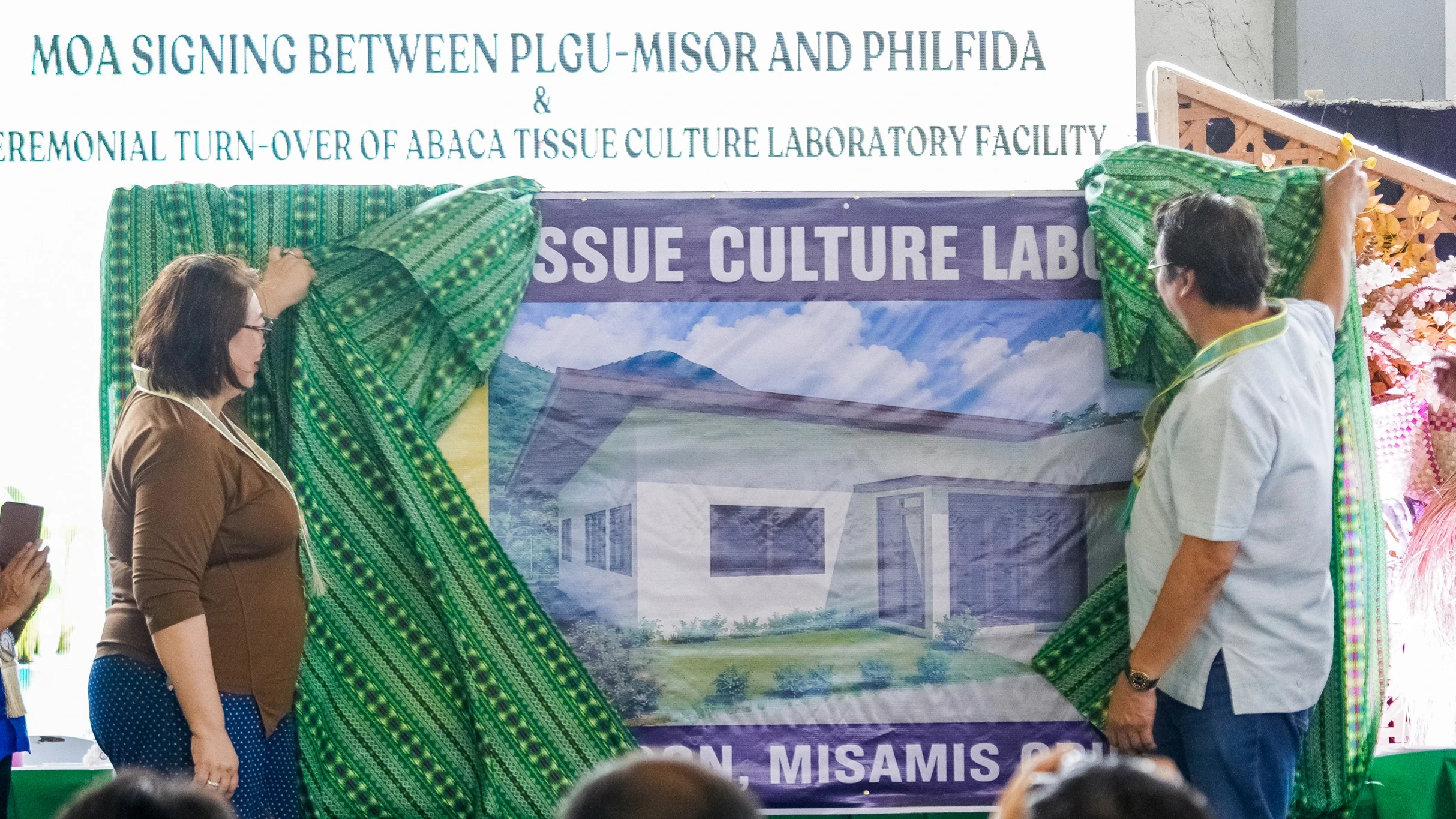 CLEAN PLANTING MATERIALS. Misamis Oriental Gov. Juliette Uy and PhilFIDA Executive Director Undersecretary Arnold Atienza present the architectural rendering of the Abaca Tissue Culture Laboratory to farmers Aug. 18 in Sugbongcogon. The facility will be repaired with PhilFIDA funding to produce clean planting materials and help prevent the spread of abaca diseases. (Photo: RMND/PIA-10/Misamis Oriental)