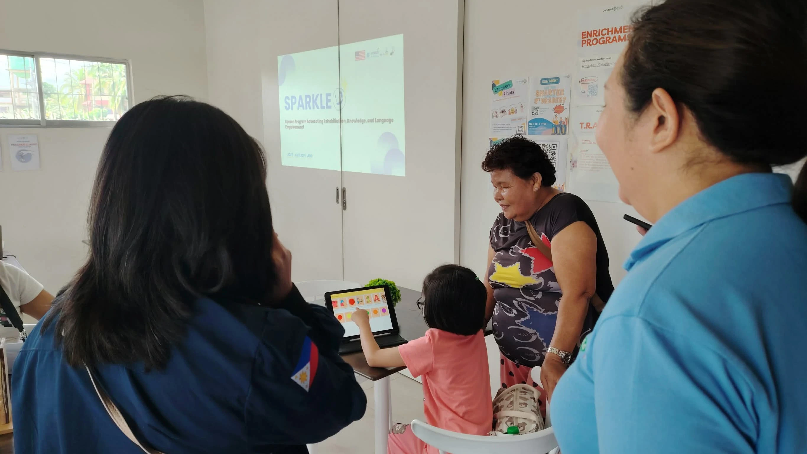 A young student uses the Pic-A-Talk app on a tablet to communicate through personalized images while caregivers and educators observe during a SPED speech empowerment program. Supplied Photo