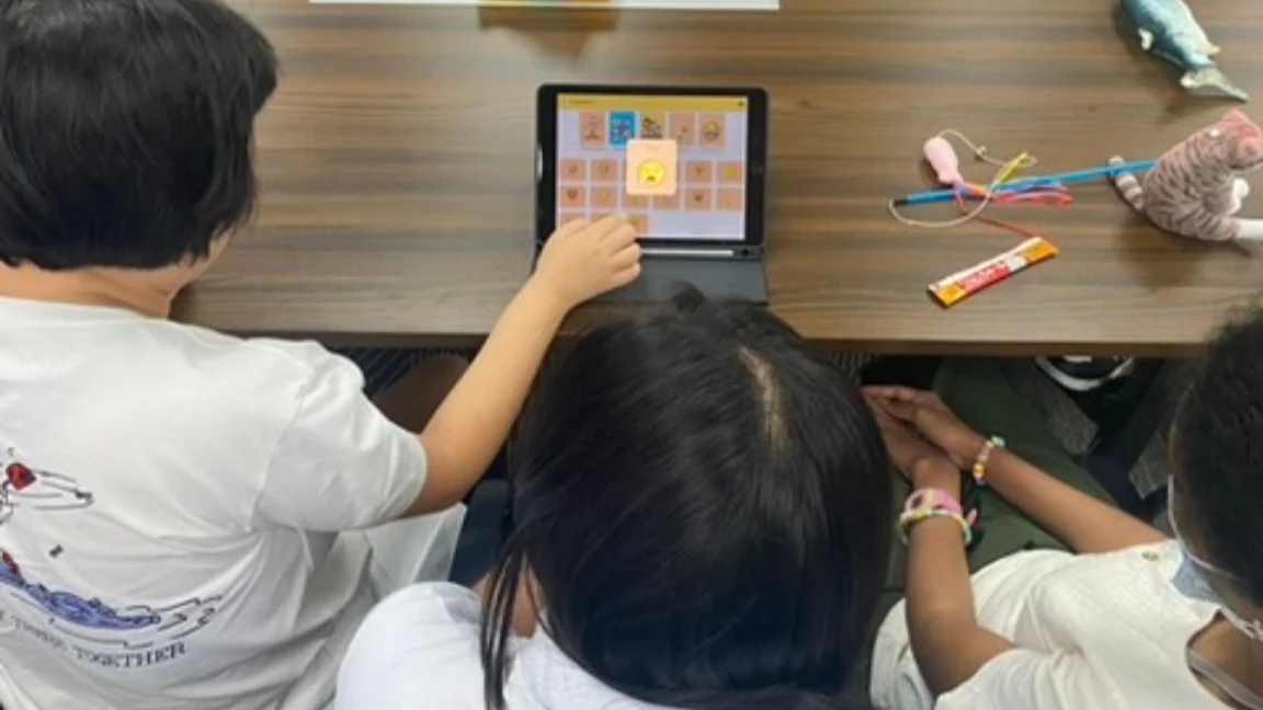 A young student uses the Pic-A-Talk app on a tablet to communicate through personalized images while caregivers and educators observe during a SPED speech empowerment program. Supplied Photo