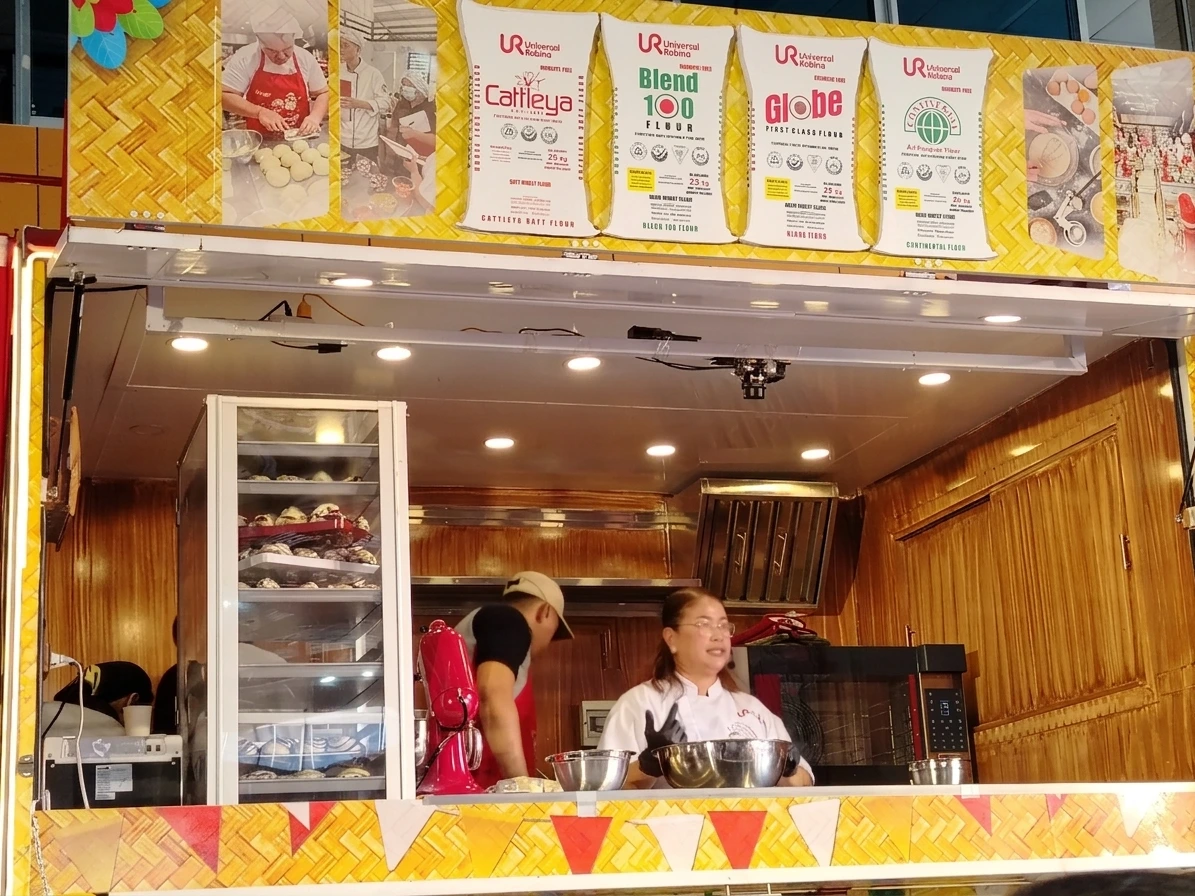 BAKING SKILLS FOR ENTREPRENEURS: Chef Aileen Asilom, URC Flour VisMin brand ambassador, demonstrates pastry-making techniques inside the Sugod Bakery Caravan truck at the City Hall covered court in Cagayan de Oro City on Aug. 25. Organized by Universal Robina Corporation during the city's Higalaay Festival, the workshop trained local bakeshop owners and home bakers on keeping pastries soft and fresh for commercial production. Photo by Shiela Mae Butlig