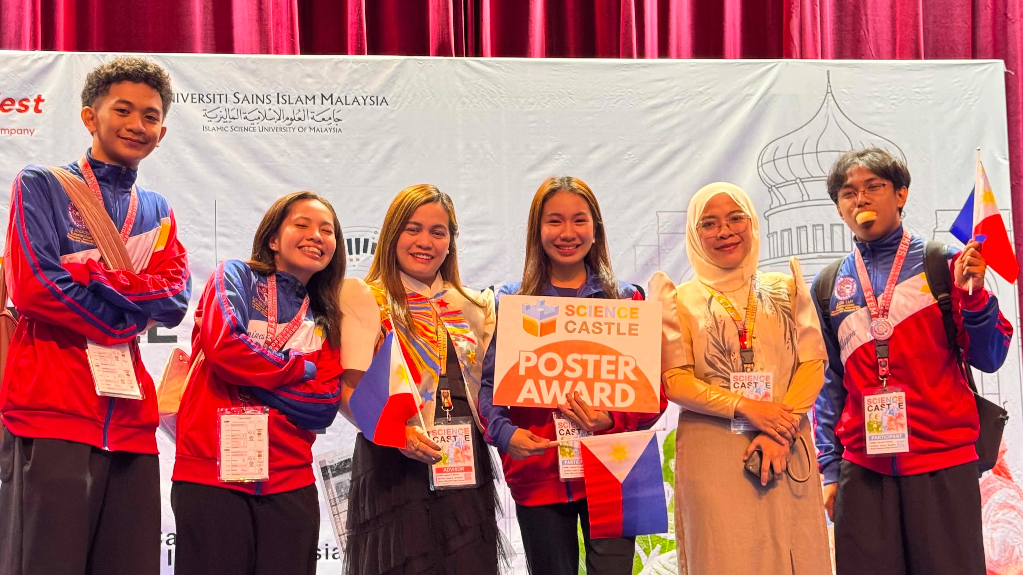 INTERNATIONAL INNOVATORS: Student researchers and faculty coaches from Acelo C. Badelles Sr. Memorial High School (ABMHS) in Iligan City celebrate on stage after winning awards at the Science Castle Asia 2026 competition at Universiti Sains Islam Malaysia in Kuala Lumpur on Aug. 28, 2026. (Photo Courtesy of Josevi D. Macas)
