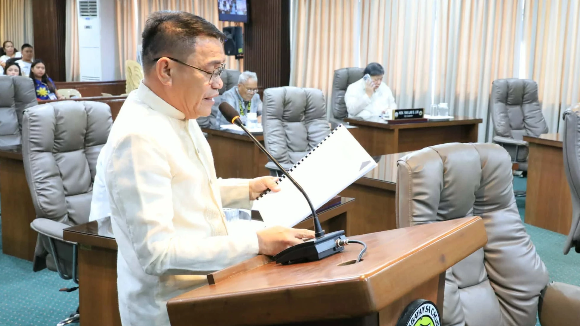 LEGISLATION FOR CDO. City Councilor and Liga ng mga Barangay President Marlo Tabac reads a legislative report at the rostrum during the Cagayan de Oro City Council's regular session. The council approved 12 key measures, including nine ordinances and three resolutions covering a ₱1.6-million prior-year procurement payment, socialized housing assistance, and agricultural and health support programs for local farmers and senior citizens. (Photo by Cagayan de Oro City Information Office)