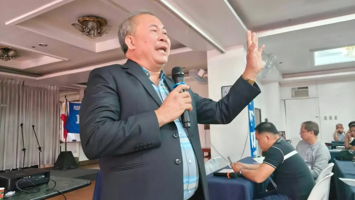 Workers Party Philippines Secretary General Atty. Allan Montaño raises a hand while holding a microphone at a podium during a labor forum on El Niño climate preparedness.