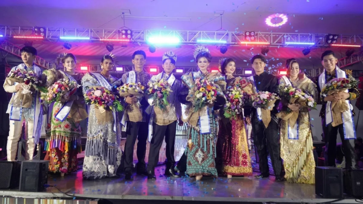 Newly crowned Mr. and Ms. Zamboanga Hermosa 2026, Baden Francis Bue and Kylie Anne Atilano, wearing crowns, sashes, and traditional attire, stand on stage holding flower bouquets alongside their runners-up as blue confetti falls at the KCC Mall Convention Center in Zamboanga City.