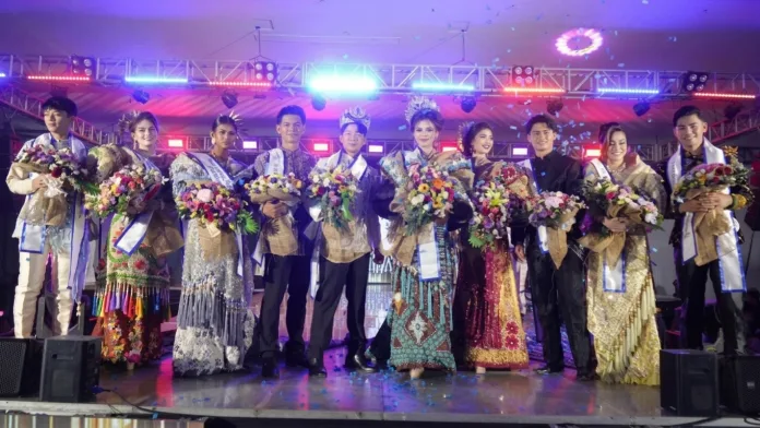 Newly crowned Mr. and Ms. Zamboanga Hermosa 2026, Baden Francis Bue and Kylie Anne Atilano, wearing crowns, sashes, and traditional attire, stand on stage holding flower bouquets alongside their runners-up as blue confetti falls at the KCC Mall Convention Center in Zamboanga City.