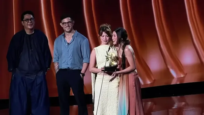 BINI members Maloi and Jhoanna accept the Artist of the Year award at the Filipino Music Awards 2026 stage while presenters look on.