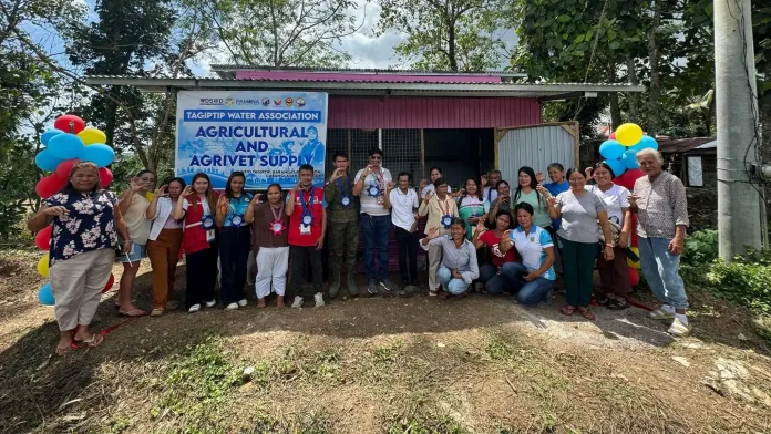 Cabanglasan Mayor Bernie Castillanes, military officials, DSWD representatives, and members of the Tagiptip Water Association pose in front of their newly turned-over agricultural and agrivet supply facility.