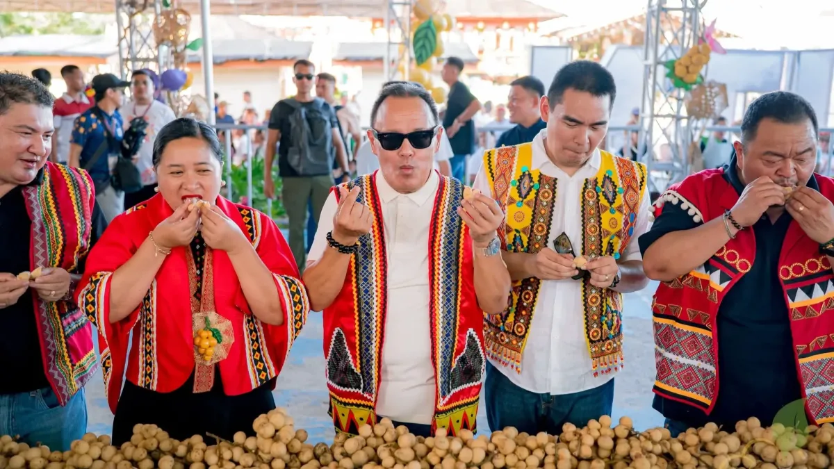 Camiguin Governor Xavier Jesus Romualdo and provincial officials wear indigenous woven vests while tasting fresh sweet lanzones at a long table during the Eat-All-You-Can Lanzones event in Camiguin.