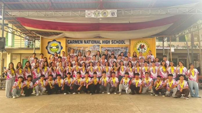 Student-athletes, coaches, and school officials of Carmen National High School Special Program in Sports wear their medals while gathering on the school stage following their 66-medal sweep at the Cagayan de Oro Division Athletic Meet 2026.