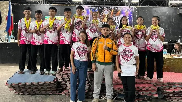 Student athletes and coaches from Carmen National High School pose with their 22 gold medals on a podium mat at the Lapasan National High School gym in Cagayan de Oro City.