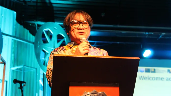 Cinemagis 16 Festival Director Dr. Hobart P. Savior addresses the audience at a podium inside the Xavier University Little Theater in Cagayan de Oro City during the opening of the 16th Northern Mindanao Film Festival.